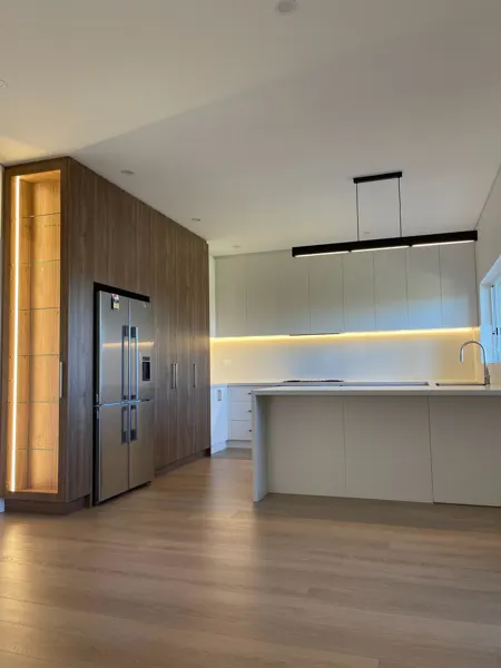 Kitchen with a black linear pendant, under-cabinet lighting and illuminated display shelving